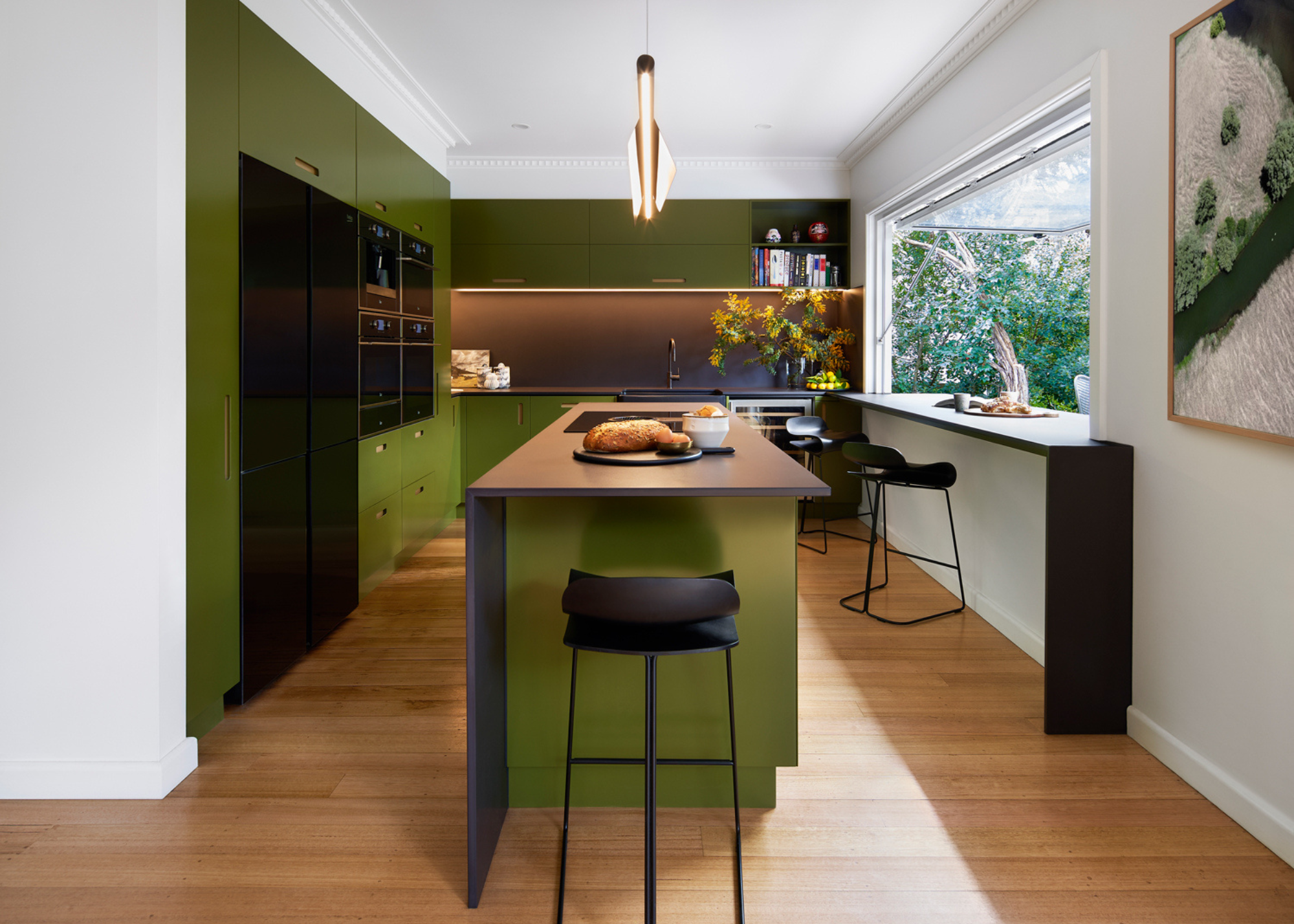A modern black and green kitchen with a central island and a large vista window adjacent