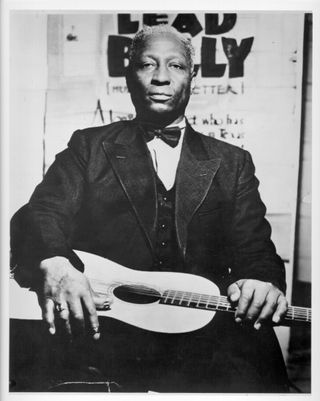 Lead Belly (born Huddie Ledbetter, 1888 - 1949) as he poses with a guitar in 1940s.