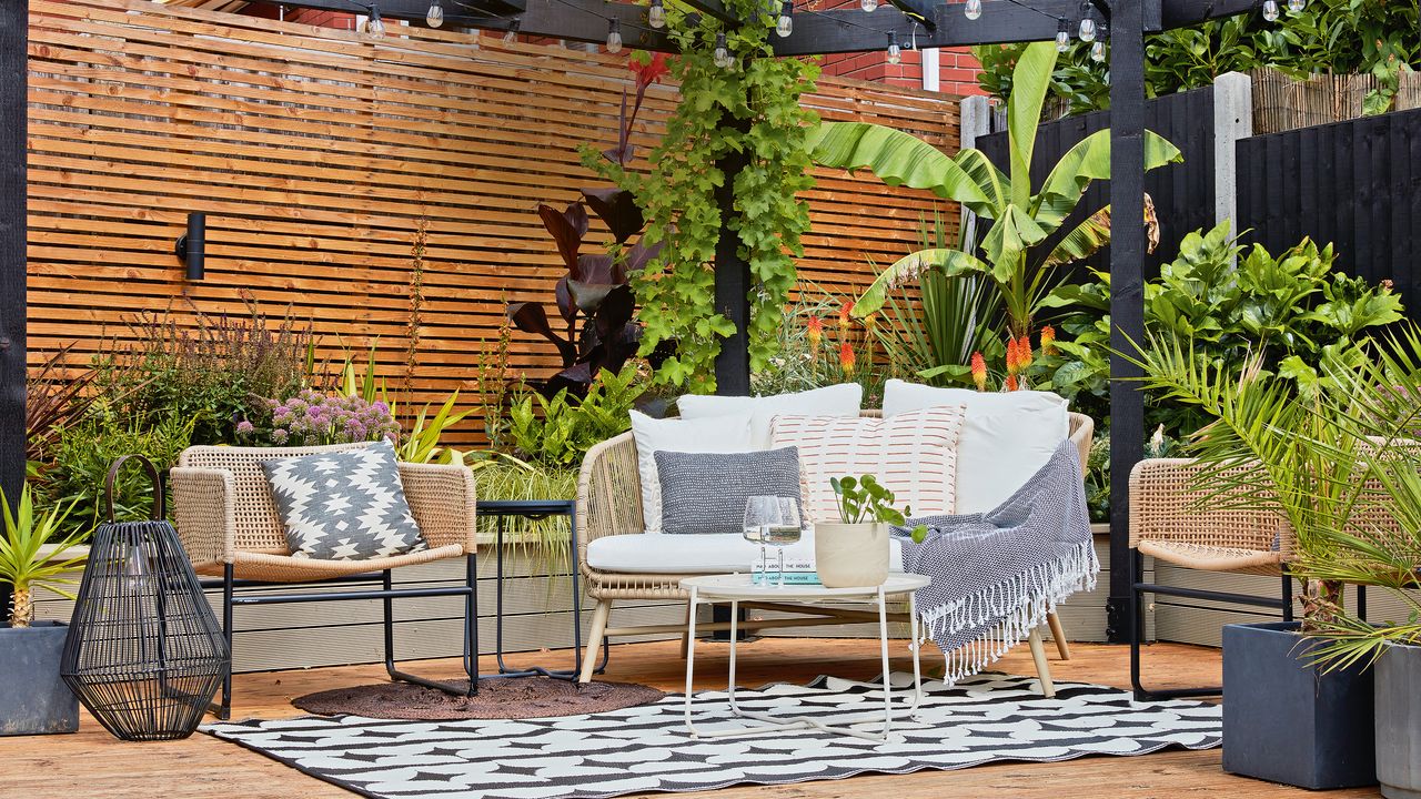 Metal chairs and table on decking with plants and stone steps and walls