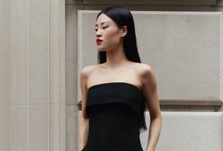 A photo of an Aritzia model wearing a strapless fitted bustier top with black trousers.