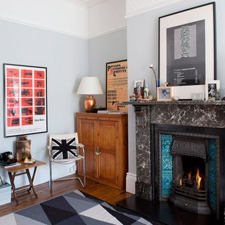 grey wall fire place with frames on wall wooden flooring