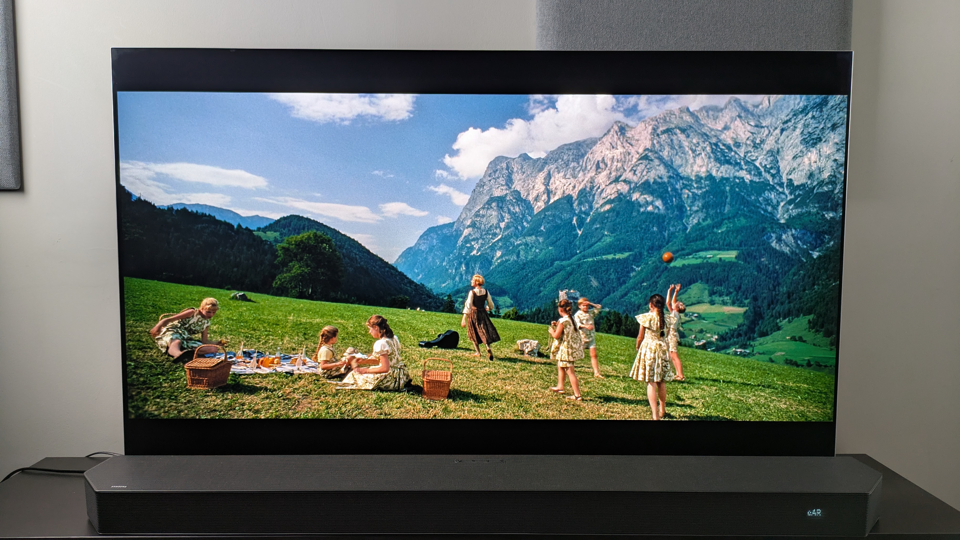 A shot of Maria and the Von Trapp children on a hillside in front of a mountain from The Sound of Music 4K Blu-ray on LG G5