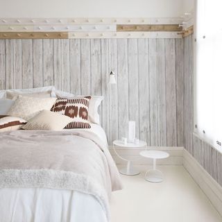 bedroom with wooden wall and white flooring and bed
