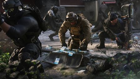 Surrounded by squadmates, a soldier kneels over a bag overflowing with cash.
