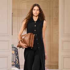 Model holding a camel-coloured brown bag on the runway