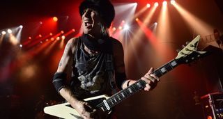 Michael Schenker wears a black felt hat and lets out a scream as he plays his black and white Dean V onstage in London.