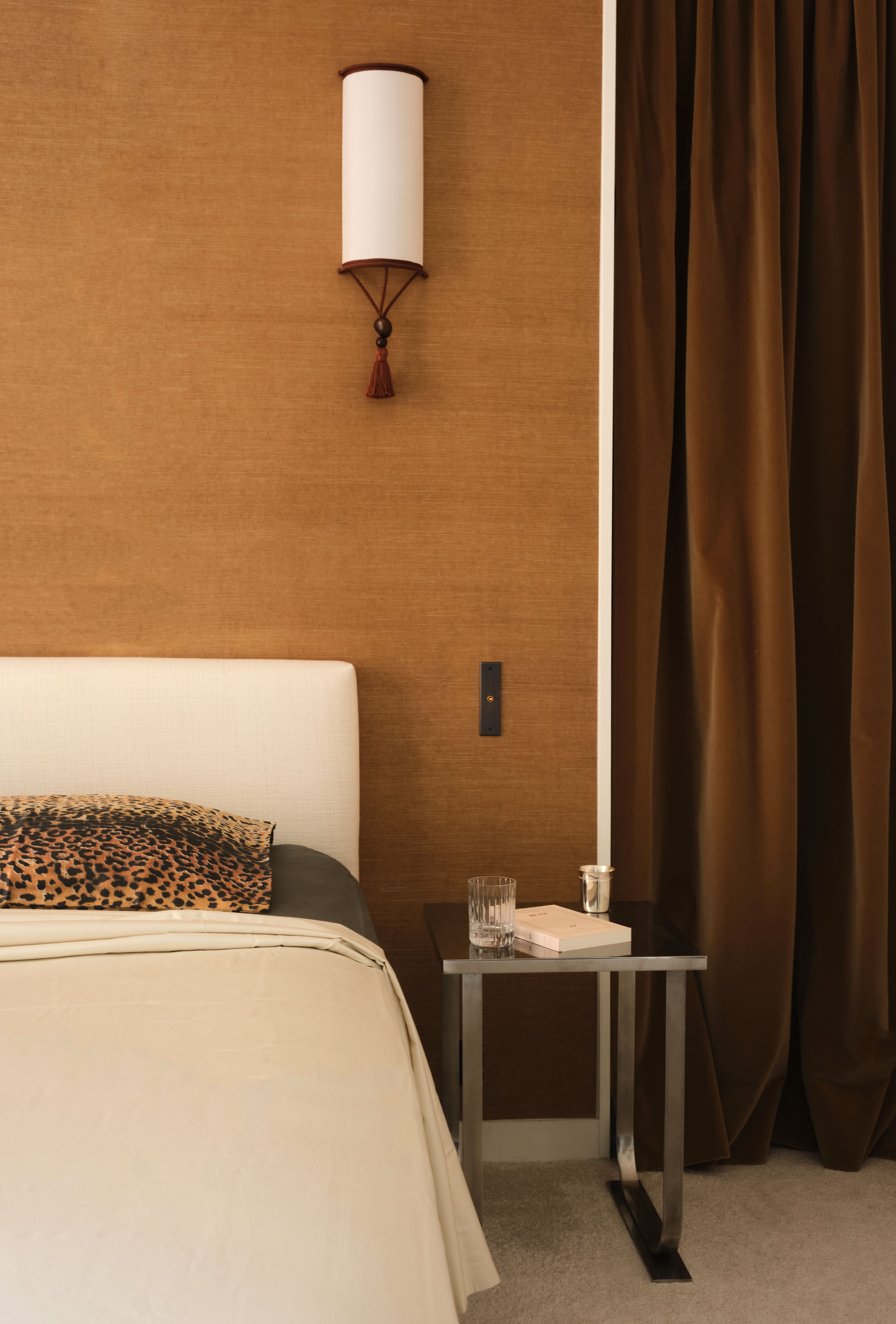 An ochre-tinted bedroom, with leopard-print cushions, Art Deco sconces, and chrome bedside tables.