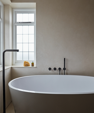 modern minimalist bathroom in pale colours with bath and floor standing tap