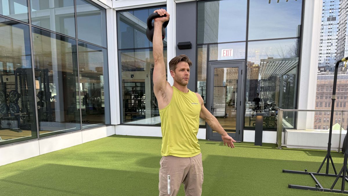 a photo of Peloton trainer Andy Speer doing a kettlebell single-arm press
