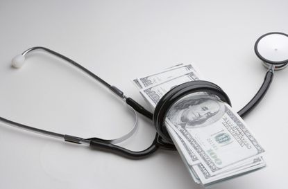 Stethoscope wrapped around hundred dollar bills