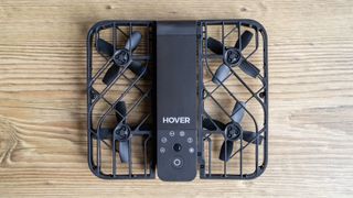 Top-down view of the HoverAir X1 drone sat on a table with cages around the propellers.