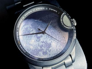 closeup of an analog wristwatch whose face features a photo of the lunar surface.