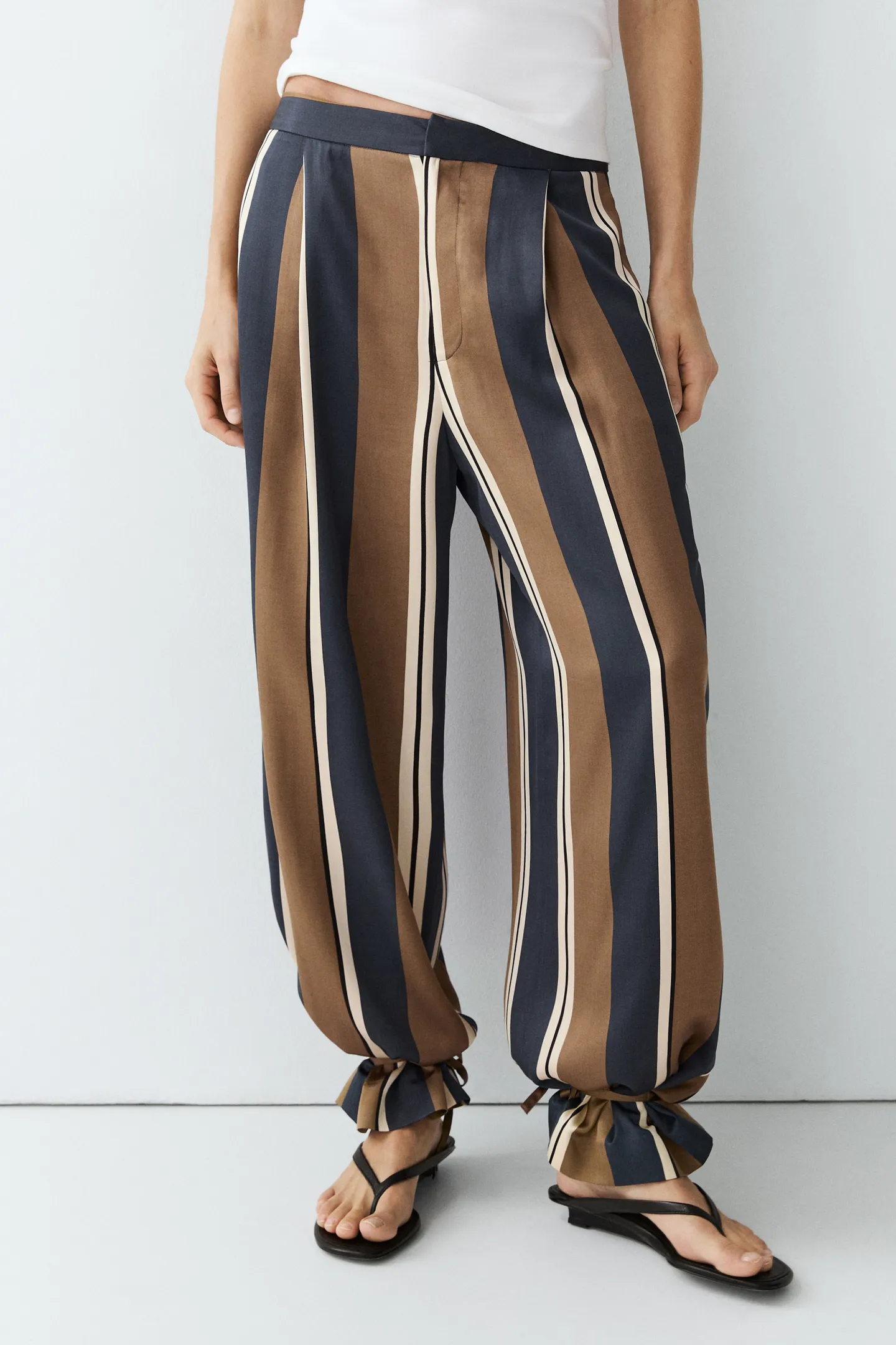 A model wears a pair of brown and navy striped Massimo Dutti balloon trousers.