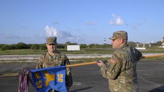 Col. Mark Shoemaker (at left), commander of the 45th Space Operations Group, and superintendent CMSgt. Omar Basnight furl and encase the group's flag at Launchpad 3, the site of the first rocket launch from Cape Canaveral, Florida in July 1950.