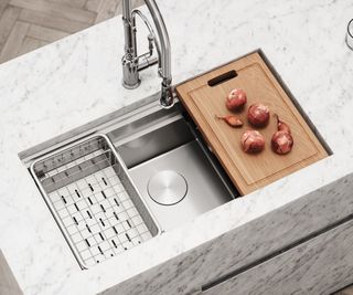 stainless steel kitchen sink with integrated chopping board and drainer inset into white and grey marble workop
