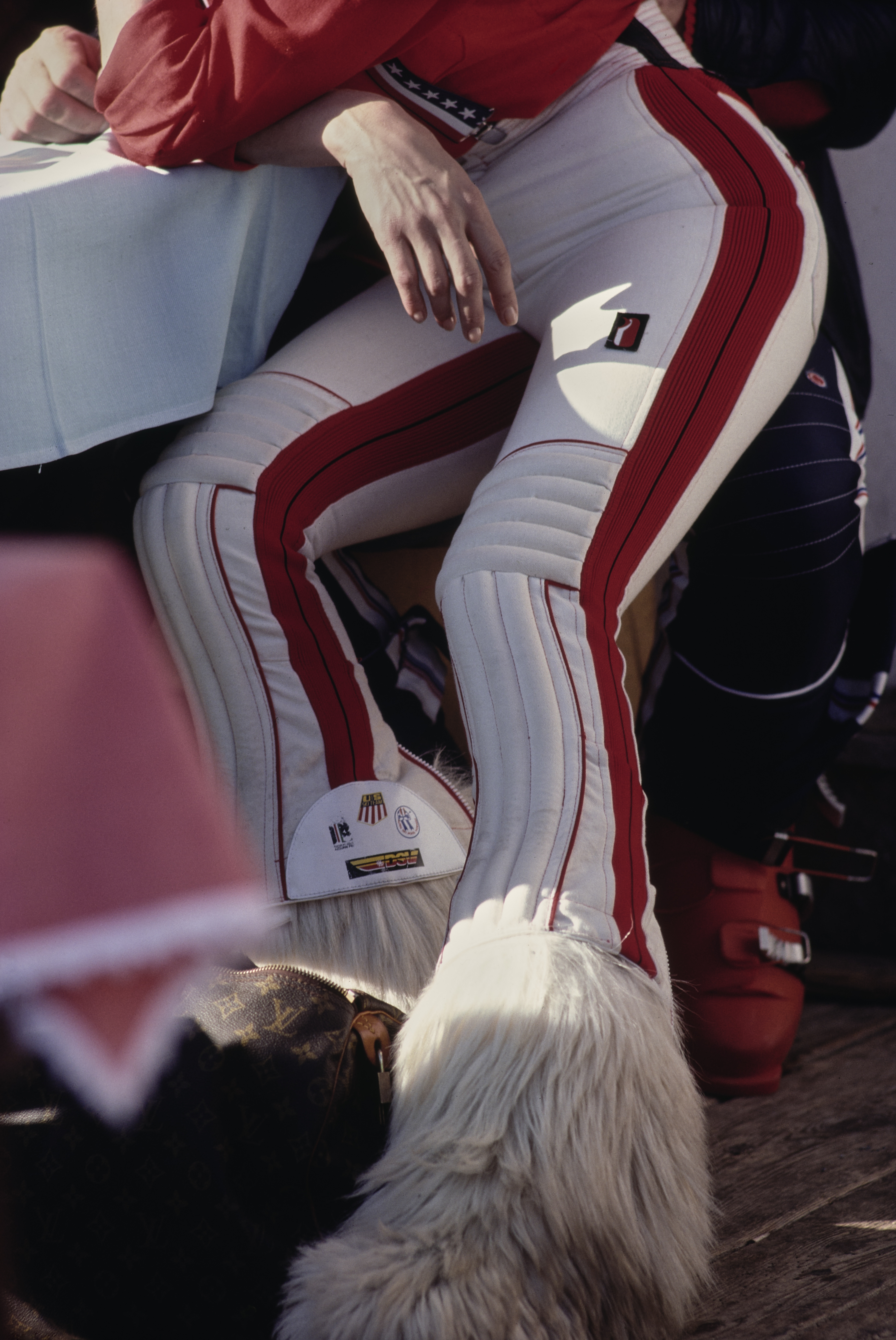 Close-up of a skier&amp;rsquo;s padded trousers and furry apr&amp;egrave;s-ski boots, showing red-and-white detailing and thick white fur trim.