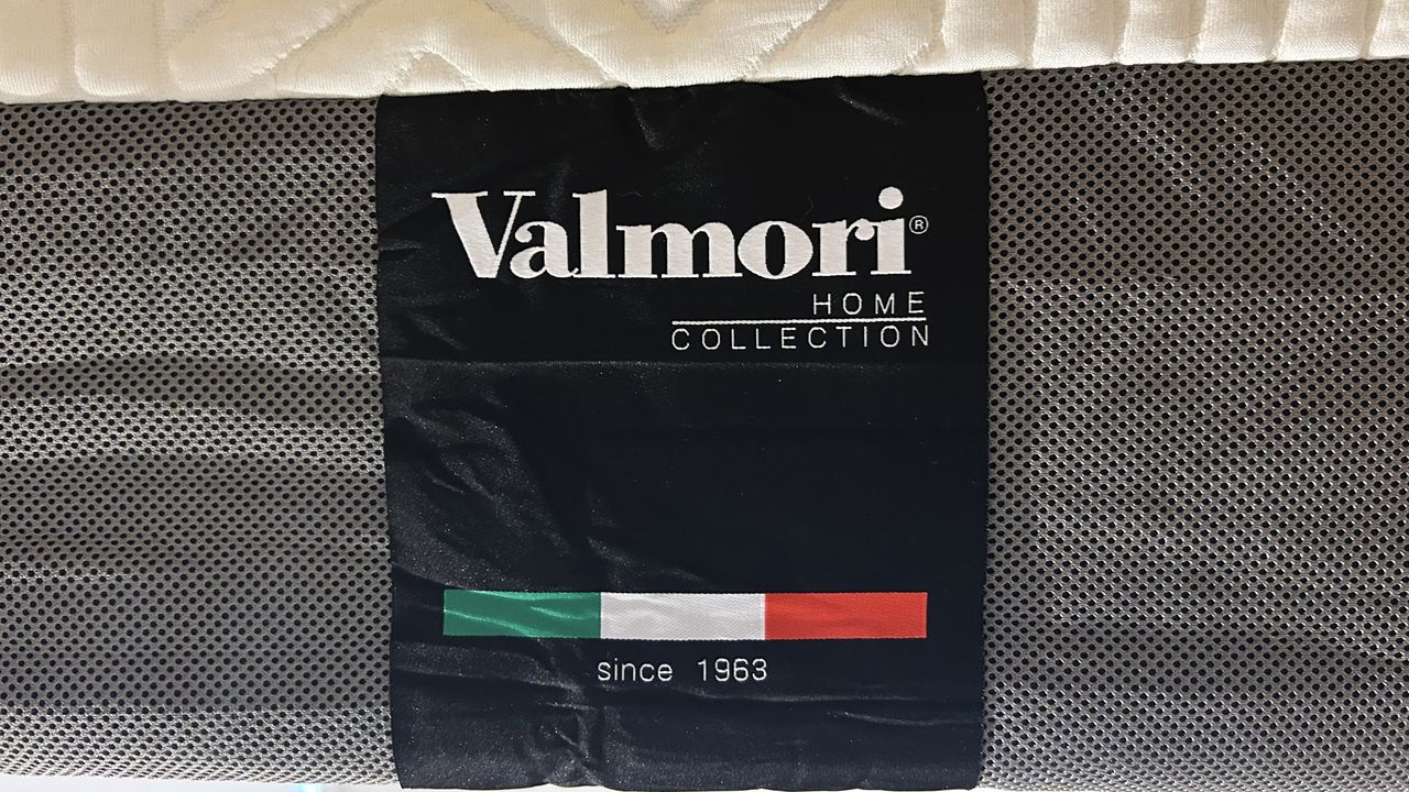 Valmori Hybrid II mattress handle and Valmori logo on black fabric with red, white and green underneath