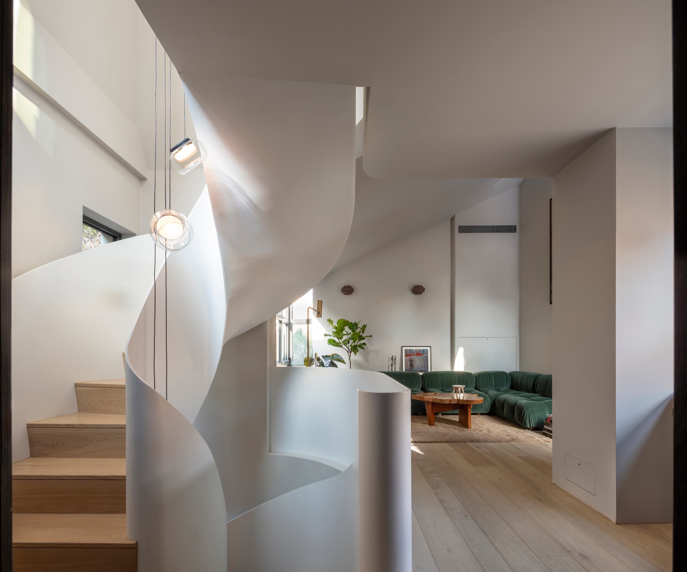 A spiral staircase with draped hanging lights in the middle that leads to a living room