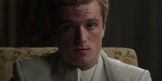 Josh Hutcherson sitting in a chair and looking intense with a white suit on.