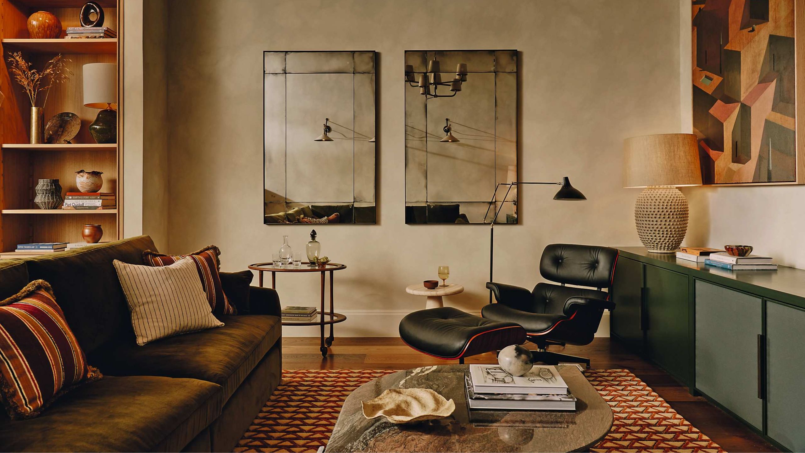 a moody bauwerk painted basement with mid century living room furniture, antique mirrors and bookshelves