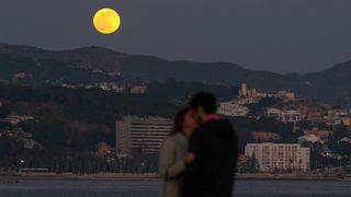 A couple kiss as the Full Wolf Moon rises over the horizon at the beach on Jan. 10, 2020, during the first lunar eclipse of the year.