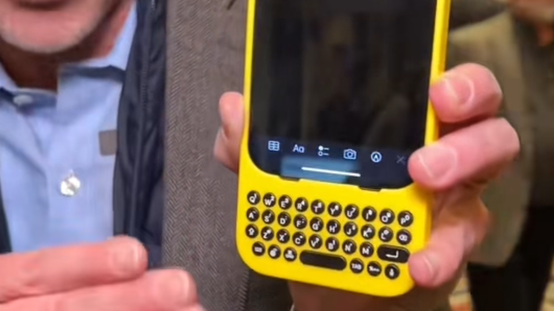 A Clicks Keyboard on an iPhone, held in a man's hand at the CES 2024 trade show