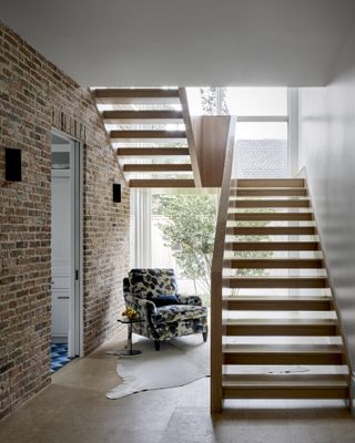 A wooden staircase rises along a vertical window