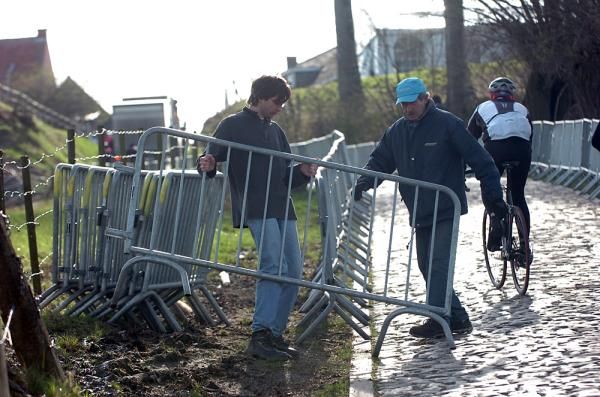 Workers begin placing the barriers on the sides of the Koppenberg climb.