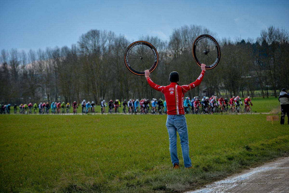 A Lotto Soudal mechanic holding spare wheels in clear sight in case of mechanicals