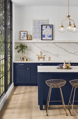A bold blue island and cabinets against marbled splashback