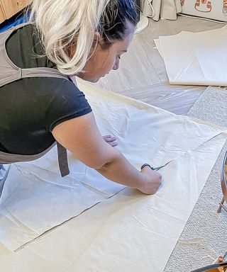 woman cutting fabric with scissors on floor