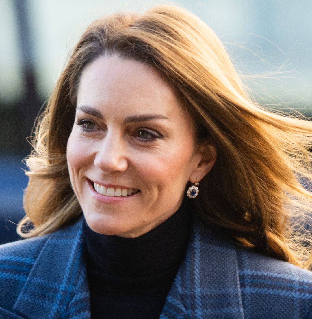 Kate Middleton smiling and wearing a blue tartan coat