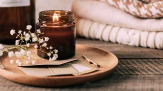 Candle mistakes - candle in brown jar lit on a wooden plate