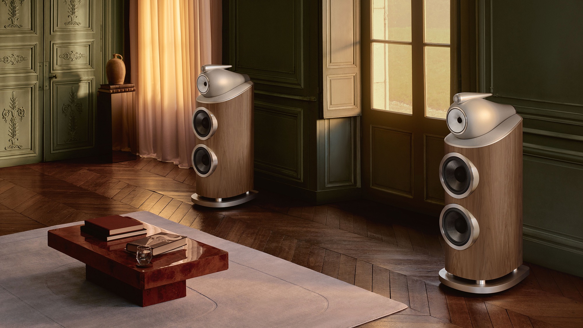 A pair of Bowers &amp;amp; Wilkins 801 D5 floorstanding speakers in the Light Walnut finish on a dark wood herringbone floor in an expensive-looking living space.