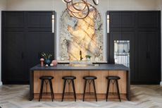 a large, arched and backlit onyx stone backsplash in the centre of tall, black kitchen cabinets in front of a black counter and wood island with four black stools