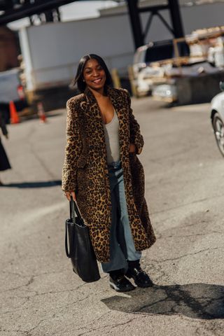 woman wearing leopard print coat, gray tank top, jeans, and boots