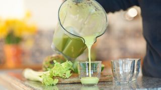 man making a green juice in his kitchen