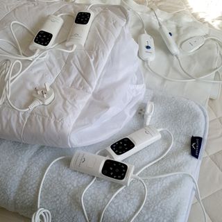 Three electric blankets, all with dual controls, being tested on a bed