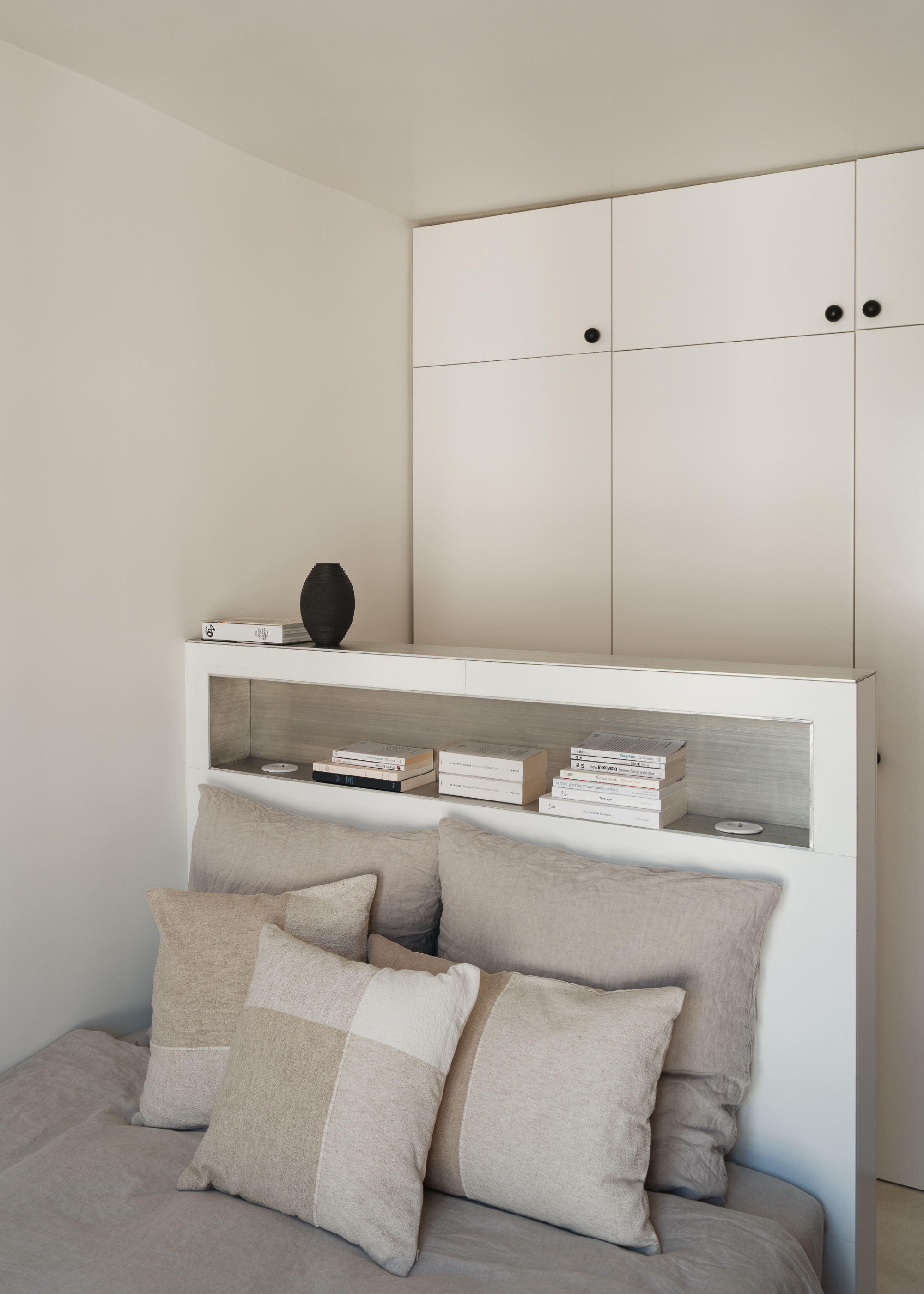 All white bedroom with a partition headboard and light grey bedding