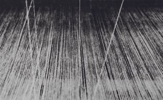 multiple white threads stretched out straight and photograph against a black background