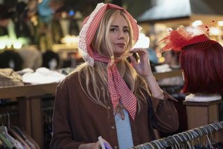 Justine Lupe as Morgan, wearing a scarf tied around her head while standing in a secondhand store, in episode 104 of Nobody Wants This.