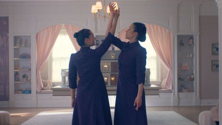 Two girls dressed in plum dance in the middle of a bedroom