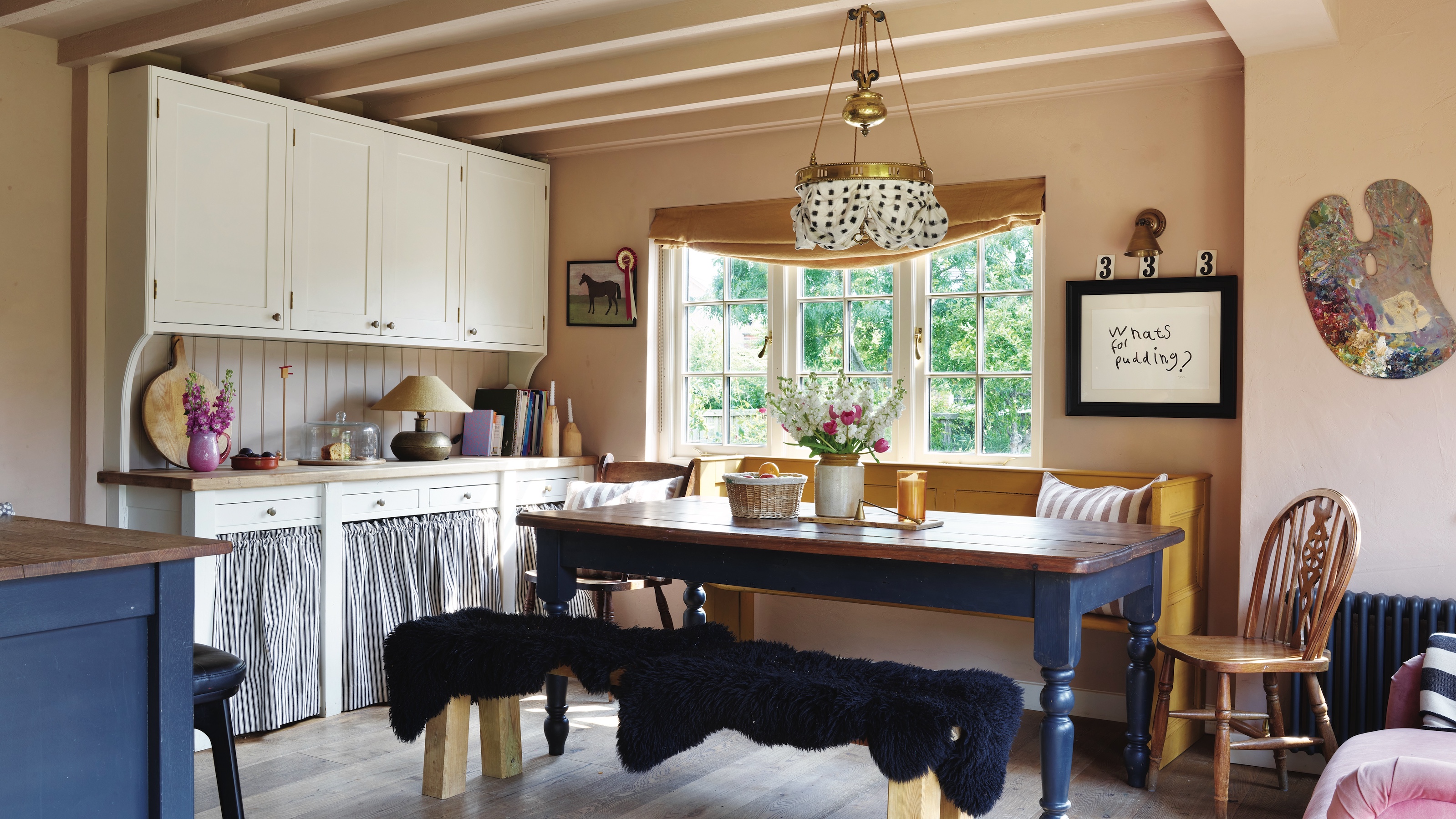 cottage kitchen with farmhouse table and bench covered with navy blue sheepskin