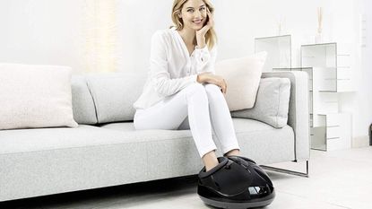 Woman sat on the sofa with her feet in the Beurer FM90, one of the best foot massagers