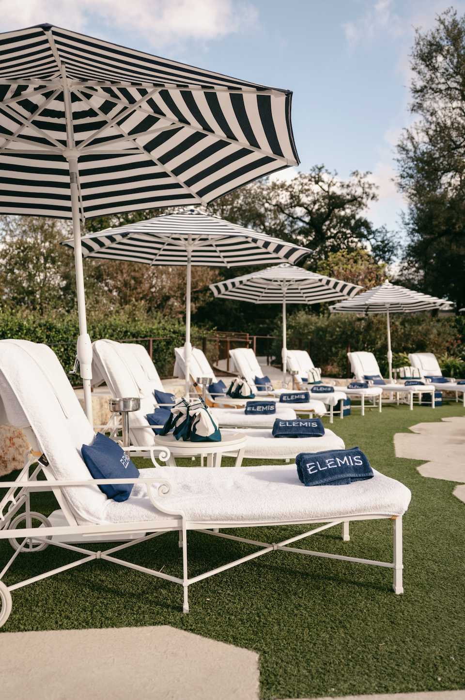 white lounge chairs on a green lawn with black and white stripe umbellas