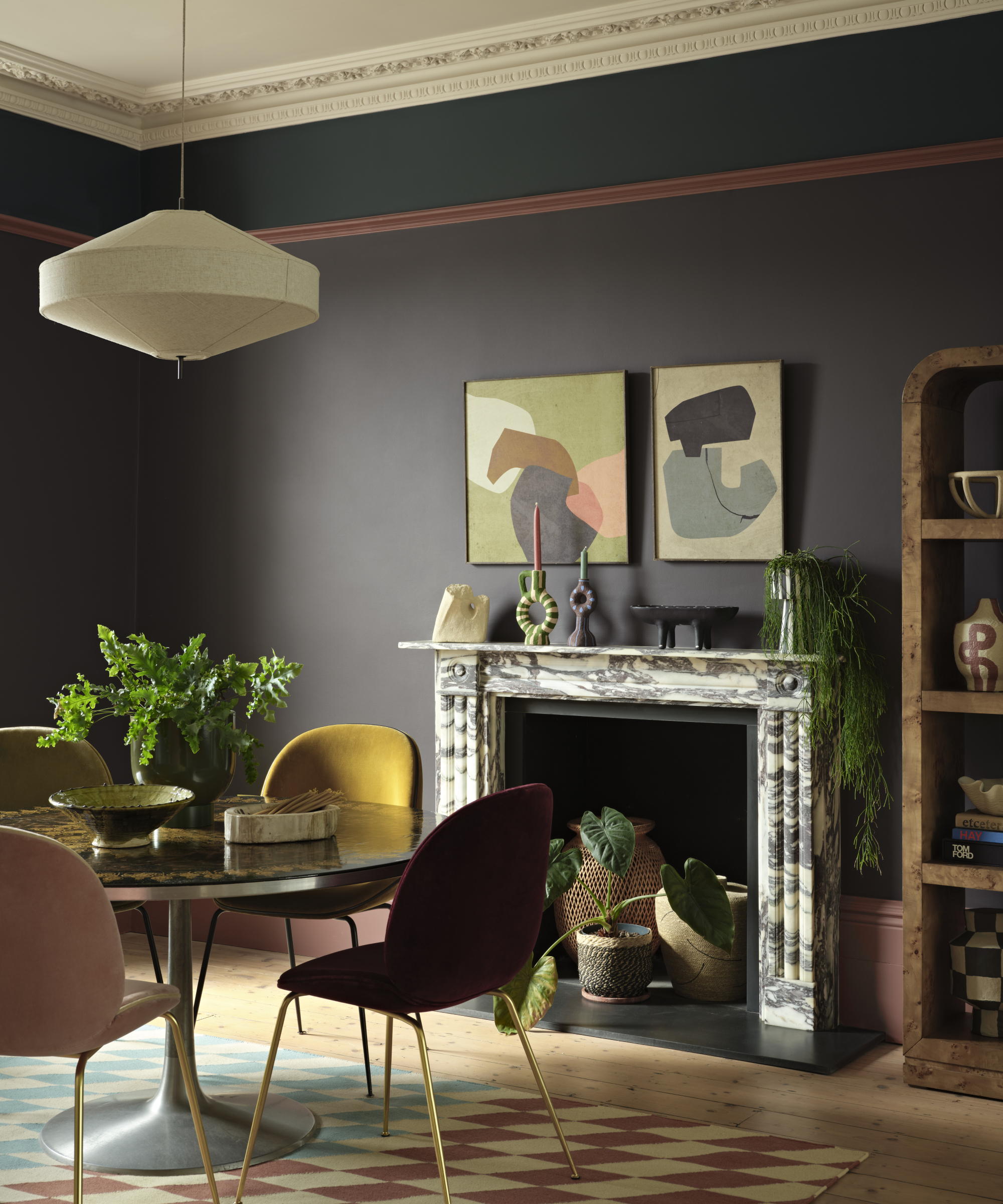 dining room with dark plum wall, burgundy picture rail and dark teal border above, marble fireplace and round dining table