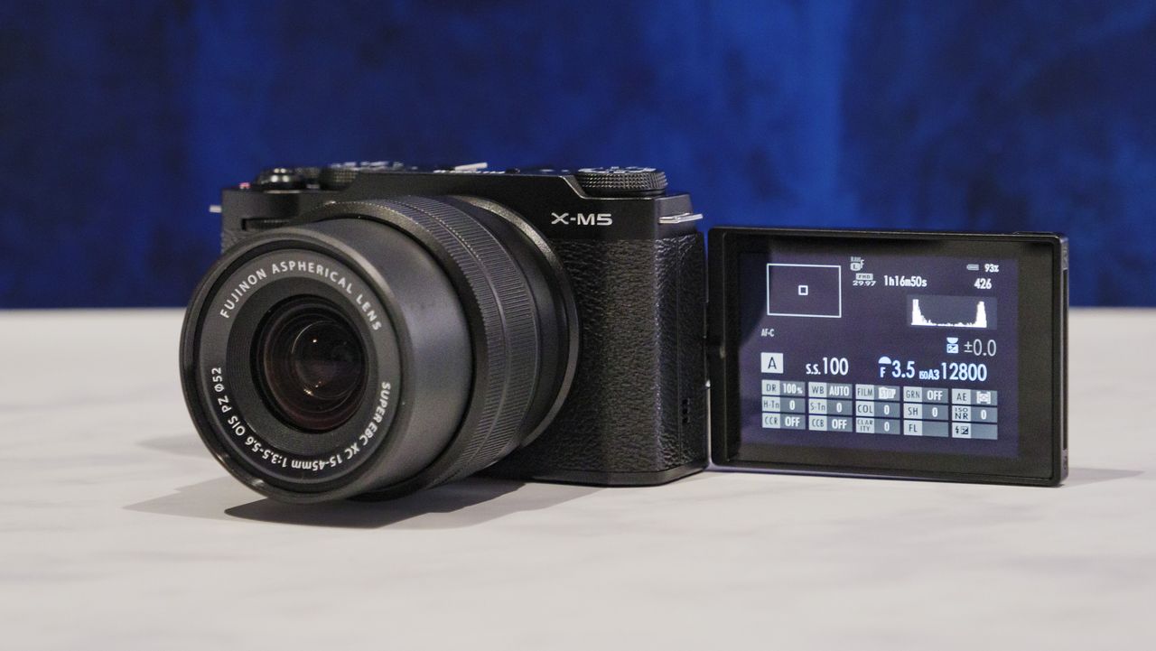 Fujifilm X-M5 camera with flip screen out, on a marble surface with rich blue background