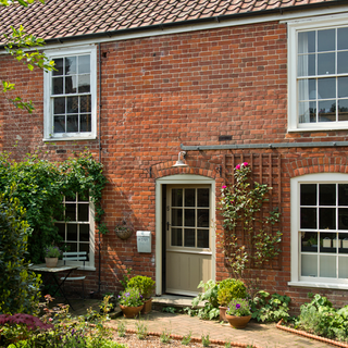 house exterior with brick wall sash windows and potted plants