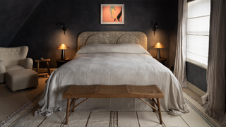 A double bed pictured in an elegant guestroom painted dark navy