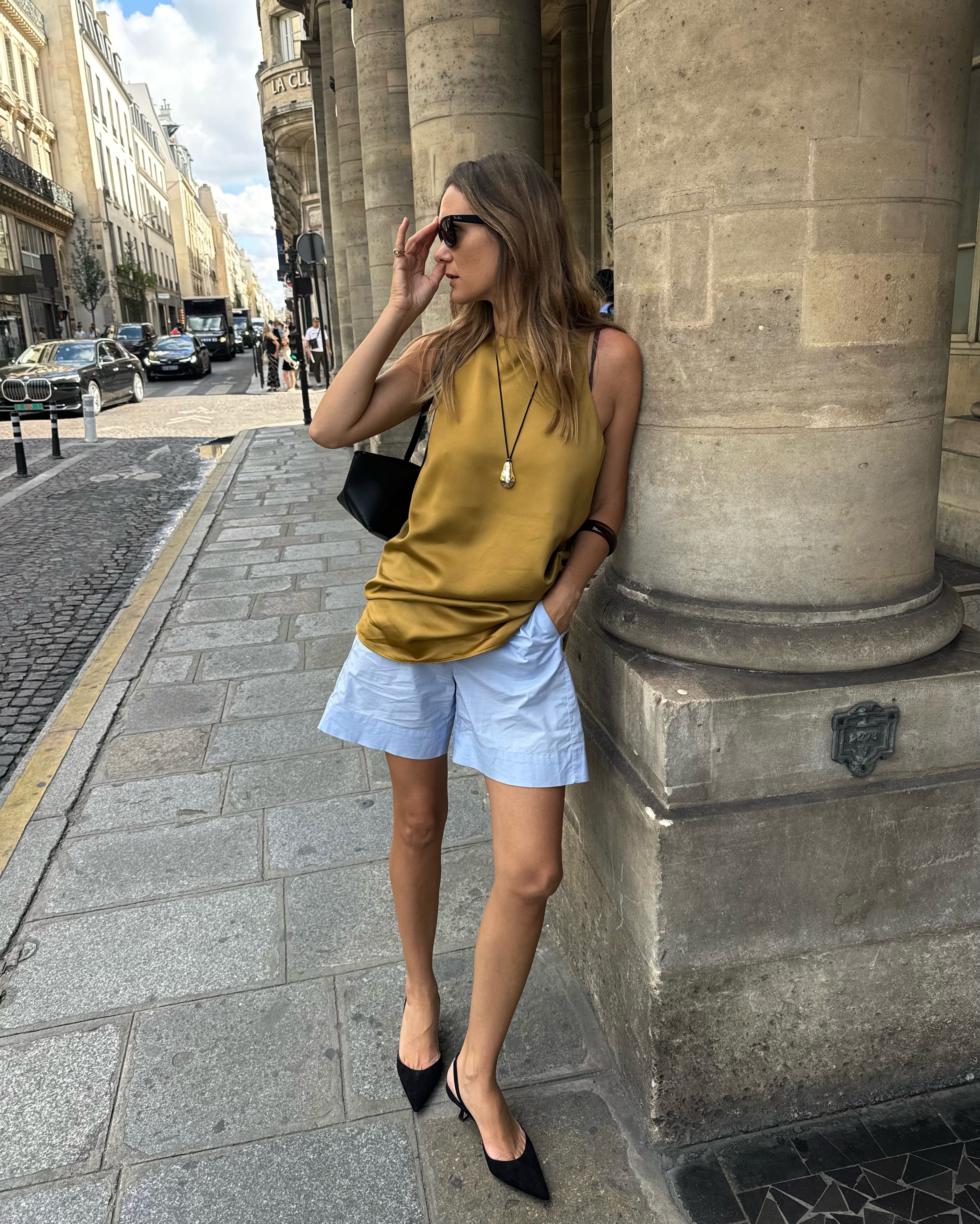 French woman wearing a satin halter top, blue cotton shorts, and black slingback pumps